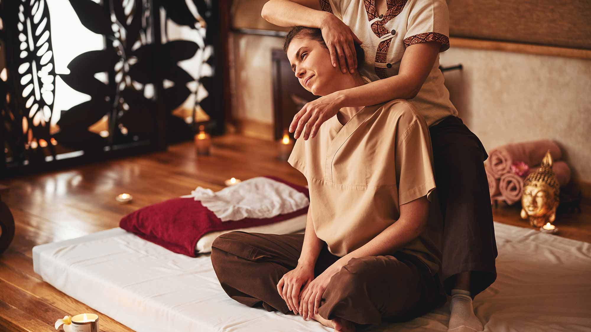 Massageprofi, der den Kopf einer Kundin nach rechts neigt